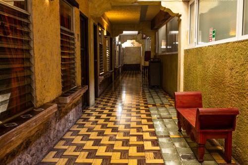 an empty hallway with a red chair and a tiled floor at Hotel La Sin Ventura in Antigua Guatemala
