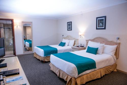 a hotel room with two beds and a television at Quality Inn Aguascalientes in Aguascalientes