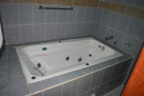 eine weiße Badewanne in einem Badezimmer mit blauen Fliesen in der Unterkunft Hotel gallego in Campeche
