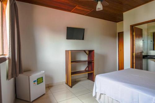 a bedroom with a bed and a tv on the wall at Topo do Cipó Ecopousada Vegana in Serra do Cipo