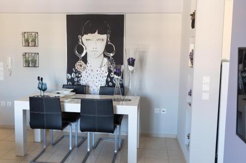 a dining room with a table with chairs and a picture of a woman at Jasmine - Apartment in Kalamata in Kalamata