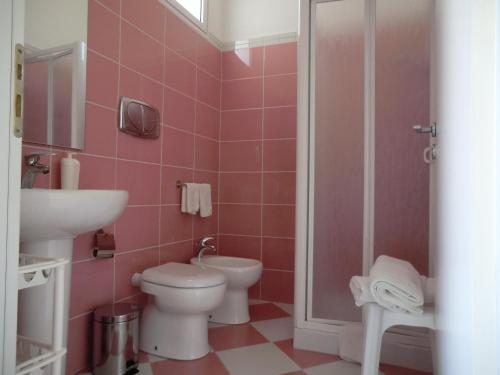 a pink bathroom with a toilet and a sink at Mediterraneo Mare e Sole in Marina di Palma