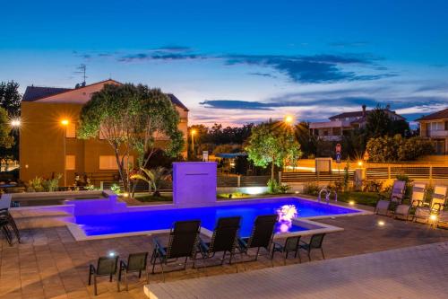 a swimming pool with chairs around it at night at Villa Zorica in Poreč