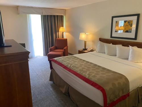 a hotel room with a large bed and a chair at Ramada by Wyndham Albuquerque Midtown in Albuquerque