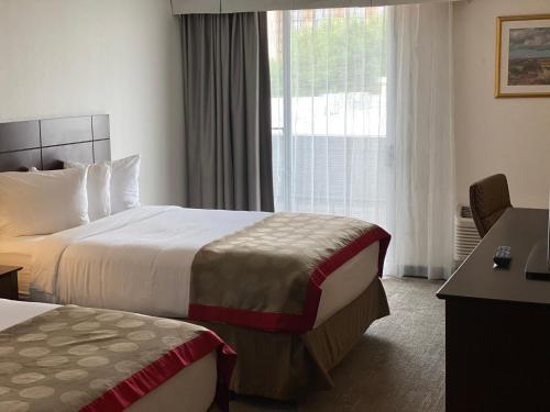 a hotel room with two beds and a window at Ramada by Wyndham Albuquerque Midtown in Albuquerque