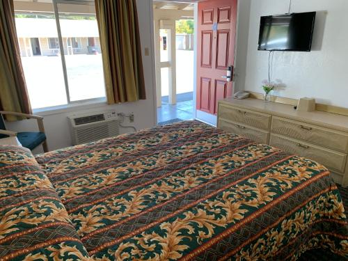 1 dormitorio con 1 cama, TV y puerta en Lark Motel Willits, en Willits