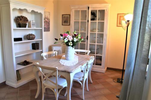 a dining room table with a vase of flowers on it at CLAUDIA VACANZA TOSCANA - Appartamento Nocciolo- 10 min da Siena in Malignano