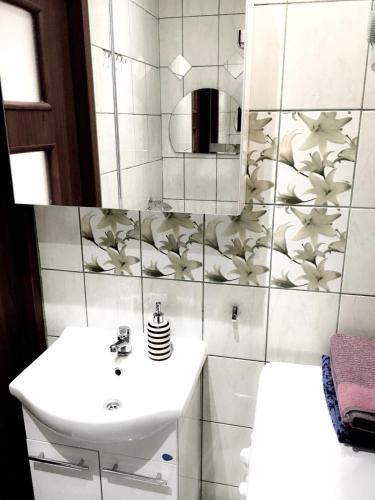 a white bathroom with a sink and a shower at Gdańsk Szklana Huta Apartament in Gdańsk