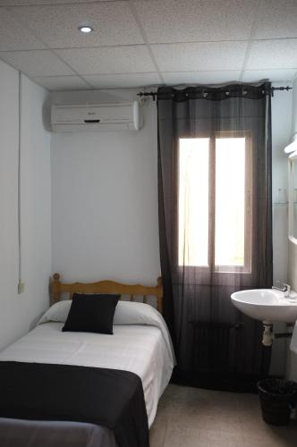 a bedroom with a bed and a sink and a window at Hostal Europa in Barcelona