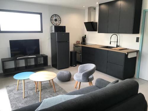 a living room with a couch and a kitchen at Jolie Maisonnette Studio in Saint-Herblain