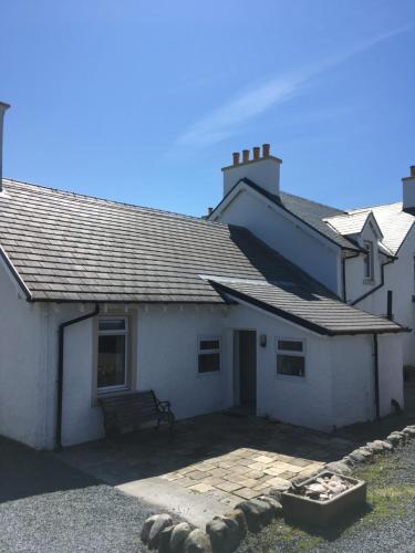 a white house with a bench in front of it at Caberfeidh Cottage in Bruichladdich