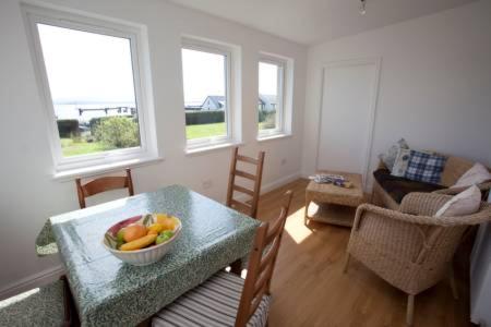 una sala de estar con una mesa con un bol de fruta. en Caberfeidh Cottage, en Bruichladdich