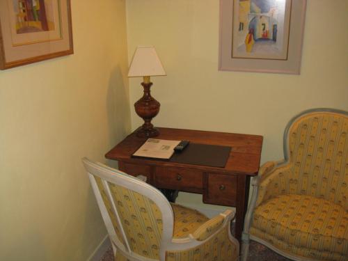 a room with a desk with two chairs and a lamp at Hotellerie de l'Esplanade in Rians