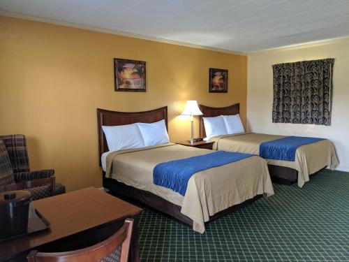 Habitación de hotel con 2 camas y mesa en Cheerio Inn - Glennville en Glennville