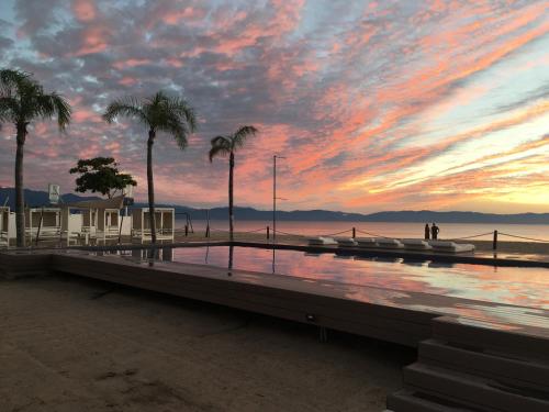 a sunset on the beach with palm trees and a pier at Estudio 310 Nuevo Vallarta, frente al mar, totalmente equipado y amueblado! in Nuevo Vallarta 