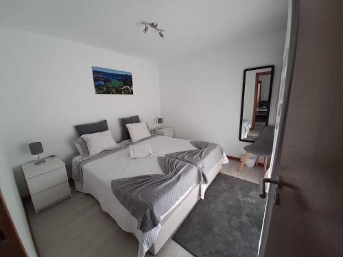 een witte slaapkamer met een bed en een spiegel bij The Furnas Azores House in Furnas