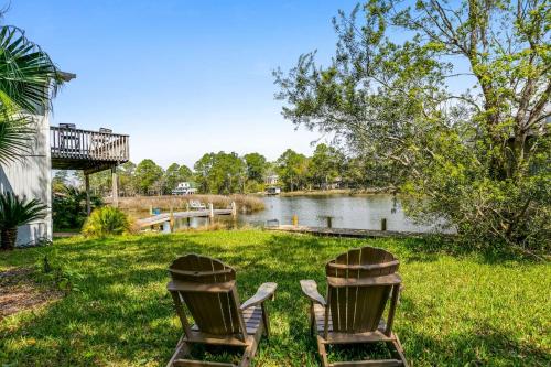 two chairs sitting in the grass next to a lake at Lone Palm on the Bayou in Pensacola