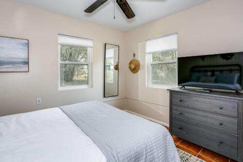 a bedroom with a bed and a dresser and windows at Lone Palm on the Bayou in Pensacola