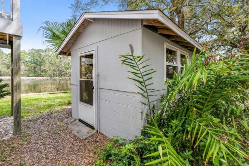 a small white shed with a door in a garden at Lone Palm on the Bayou in Pensacola