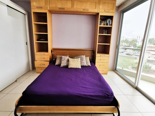 - une chambre avec un lit violet dans une pièce dotée de fenêtres dans l'établissement Estudio 310 Nuevo Vallarta, frente al mar, totalmente equipado y amueblado!, à Nuevo Vallarta