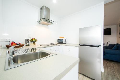 a white kitchen with a sink and a refrigerator at New England Motor Lodge in Glen Innes