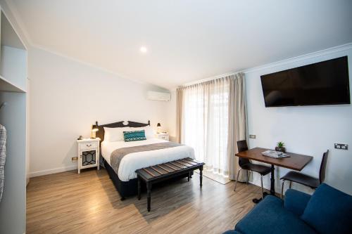 a bedroom with a bed and a tv and a couch at New England Motor Lodge in Glen Innes