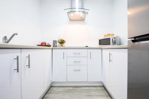 a white kitchen with white cabinets and a microwave at New England Motor Lodge in Glen Innes