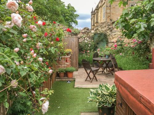 un jardín con rosas, mesa y sillas en Beech View en Malton