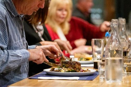 a woman cutting into a plate of food on a table at New England Motor Lodge in Glen Innes