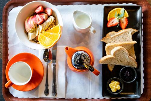 a breakfast tray with toast bread and fruit and a cup of coffee at New England Motor Lodge in Glen Innes