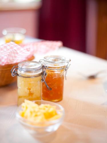 two jars of jam and a bowl of food on a table at Andelomi Forest Lodge in Stormsrivier