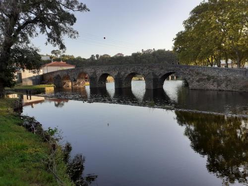 un puente de piedra sobre un río con un reflejo en el agua en Casa da Praça, en Sertã