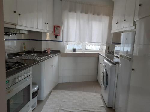 a kitchen with white cabinets and a sink and a dishwasher at Casa da Praça in Sertã