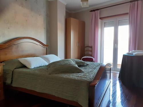 a bedroom with a bed and a large window at Casa da Praça in Sertã