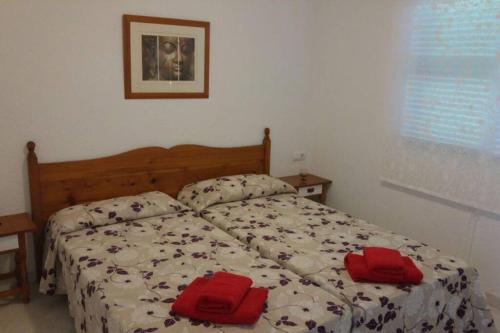 una camera da letto con un letto con due cuscini rossi sopra di TRANQUILO APARTAMENTO con preciosa cala en la puerta a Ciutadella