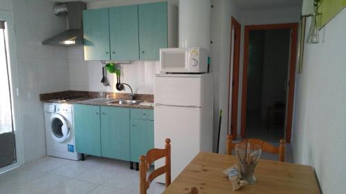 a kitchen with a refrigerator and a table with a microwave at TRANQUILO APARTAMENTO con preciosa cala en la puerta in Ciutadella