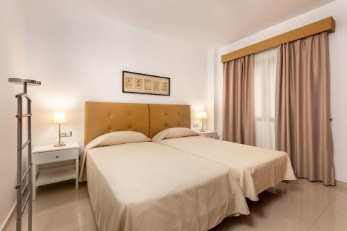 a bedroom with a large white bed and a window at Apartamentos Las Palmeras in Puerto de Mogán