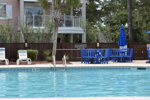a pool with blue chairs and umbrellas next to a house at 503M villa in Calabash