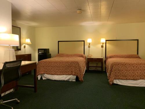 a room with two beds and a desk and lamps at St. Mary’s Motel 