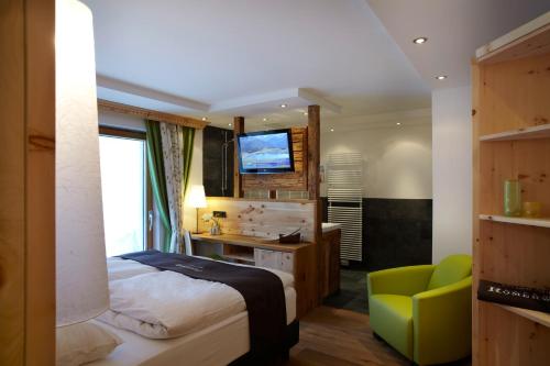 a bedroom with a bed and a desk and a television at Hotel am Römerweg in Fiss