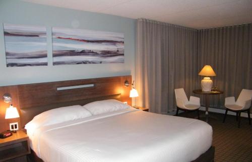 a hotel room with a large white bed and chairs at Auberge De La Baie in Caraquet