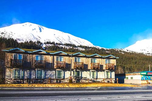 un grand bâtiment avec une montagne enneigée en arrière-plan dans l'établissement Murphy's Alaskan Inn, à Seward