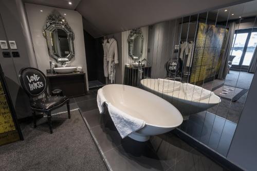 a bath room with a tub and a toilet at The Exhibitionist Hotel in London