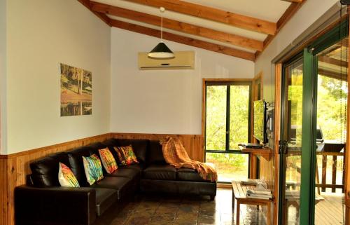 sala de estar con sofá de cuero negro en Diamond Forest Farm Stay, en Manjimup