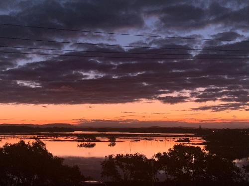 a sunset over a body of water with clouds at Wallis View 13 in Forster