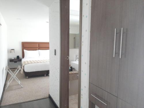 a bedroom with a bed and a bathroom with a mirror at Pontevedra Hotel Boutique in Paipa