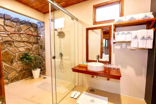 a bathroom with a glass shower and a sink at Golden Topaz Phu Quoc Resort in Phu Quoc