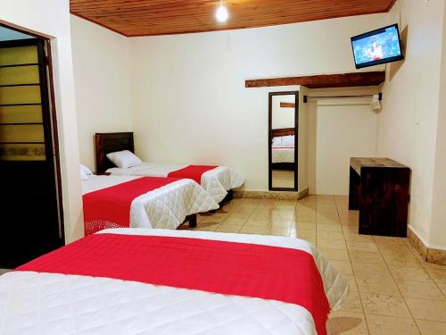 a room with three beds and a tv on the wall at HOTEL CASA D'LINA CENTRO in San Cristóbal de Las Casas