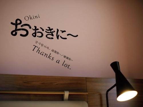a room with a lamp and a wall with a sign that says wisdom strengthens me at DEL style Osaka Shin Umeda by Daiwa Roynet Hotel in Osaka