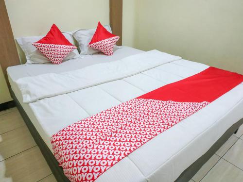 a bed with red and white sheets and pillows at OYO 3871 Hotel Surya in Pontianak